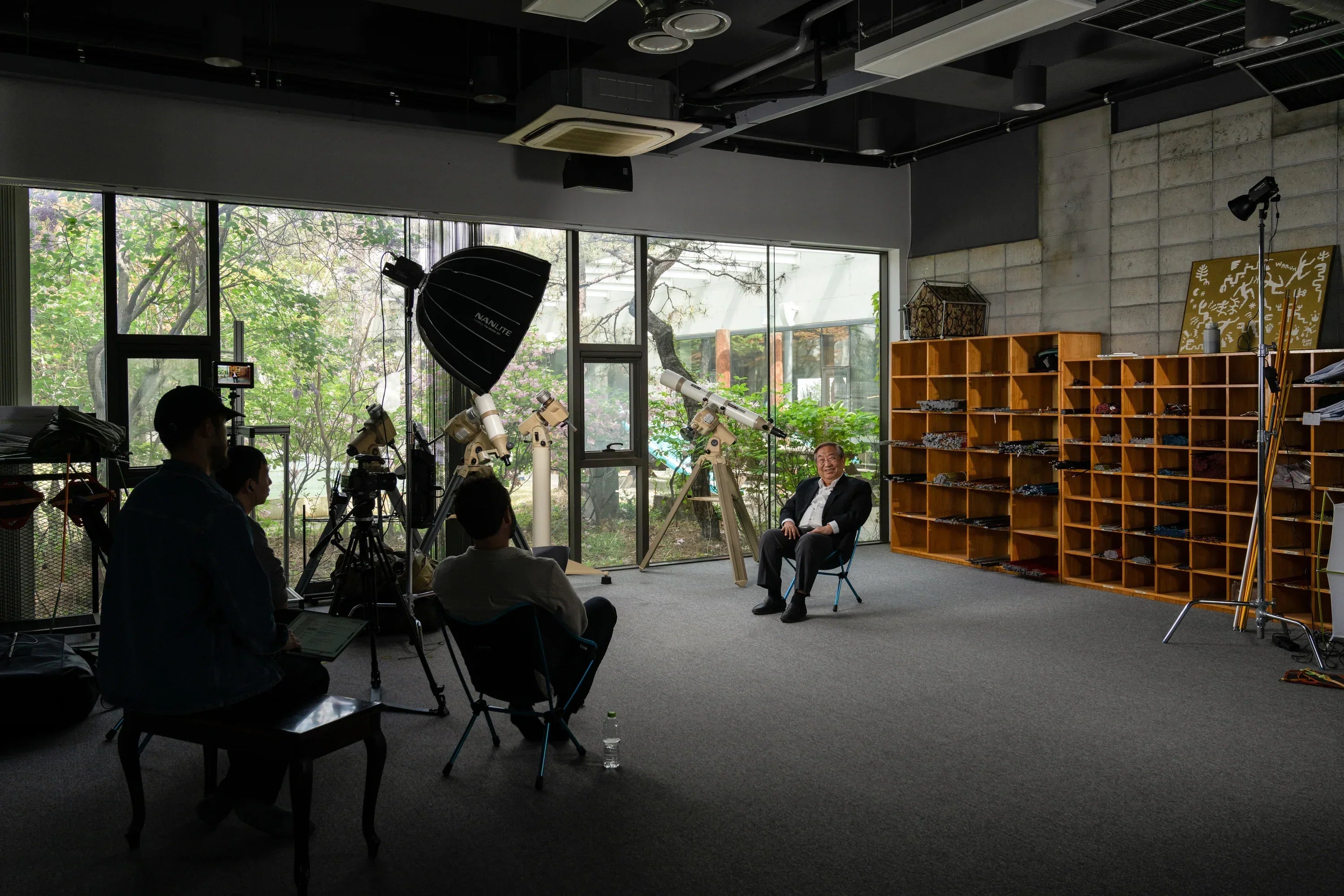 A person sitting on a camping chair for an indoor film production setup.